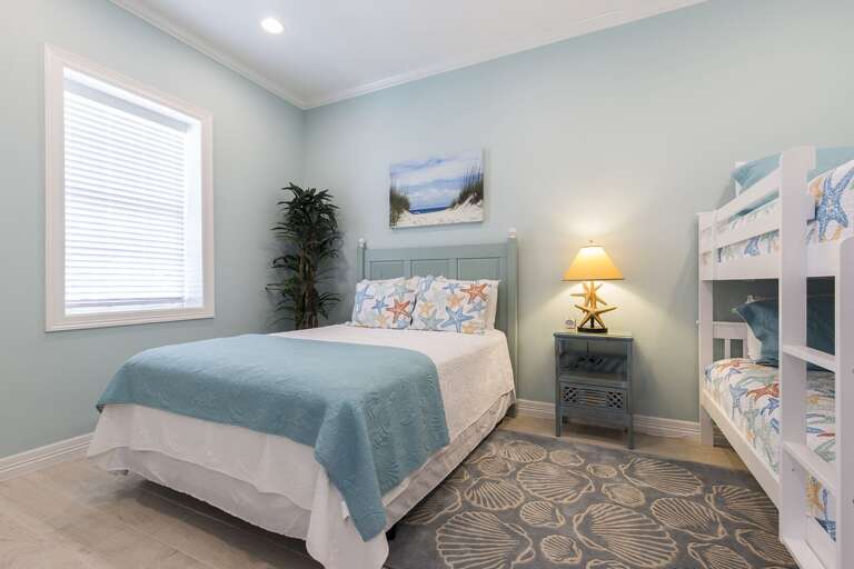 Downstairs bedroom with a queen bed and twin bunk beds!