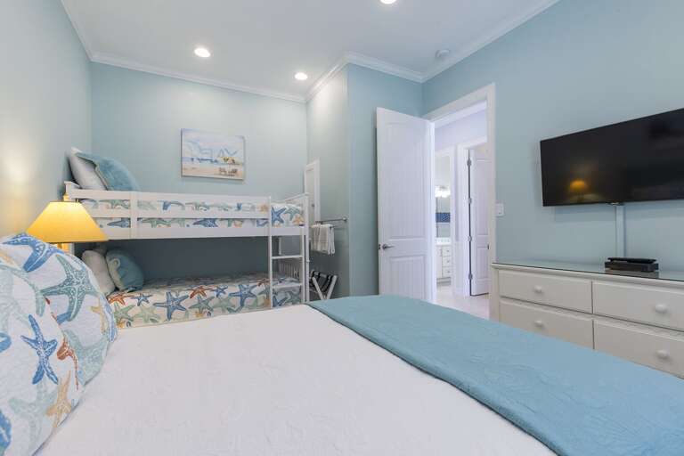 Downstairs bedroom with a queen bed and twin bunk beds!