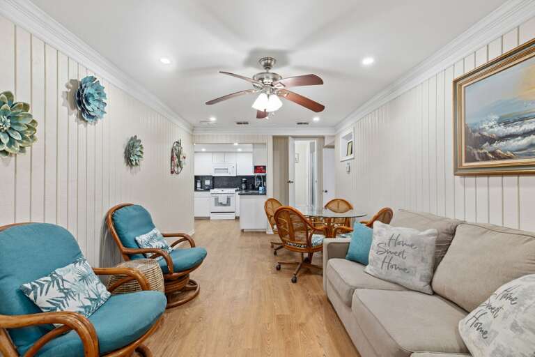 Light-filled Living Space With Blue Chairs, Beige Sofa, Wooden Floor, And Ceiling Fan Light-filled Living Space With Blue Chairs, Beige Sofa, Wooden Floor, And Ceiling Fan