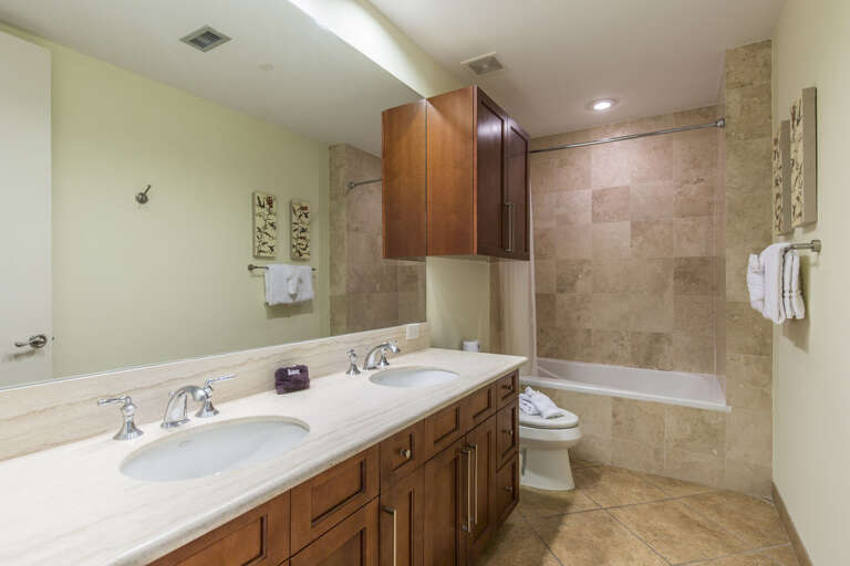 Shared guest bathroom features combination bathtub and shower & double vanity.
