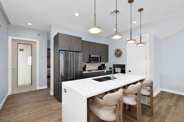 Interior Kitchen View With Bar Stools, Pendant Lights, And Stainless Steel Appliances Interior Kitchen View With Bar Stools, Pendant Lights, And Stainless Steel Appliances