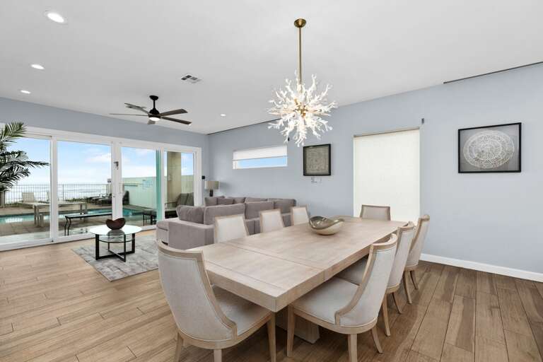Spacious Seaside Dining Space With Sleek Table Set And Sparkling Chandelier Spacious Seaside Dining Space With Sleek Table Set And Sparkling Chandelier