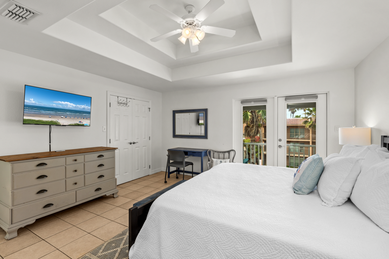 Master bedroom with king bed and private balcony overlooking the pool.