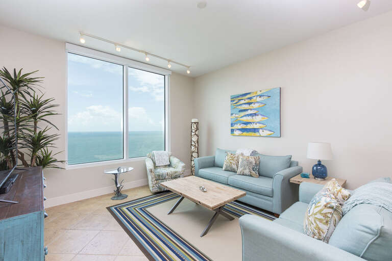 Bright and spacious living room with flat screen TV and views of the beach!