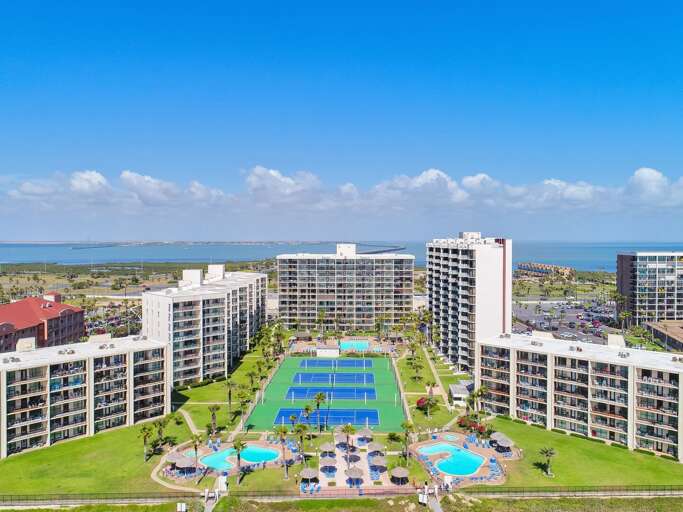 Aerial View Of Seaside Structures With Pools And Lush Lawns