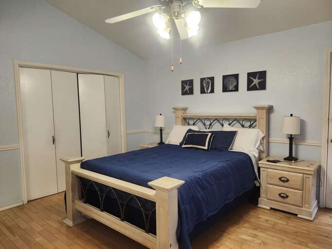 The master bedroom features a comfortable queen-size bed, a standard futon, and a flat-screen TV, offering sleeping space for up to 4 guests.