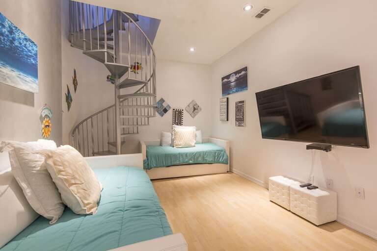 Guest room with 4 twins (2 trundles). This is an open concept room/media room that is included as one of the 4 total bedrooms. Staircase leads to the roof-top deck!