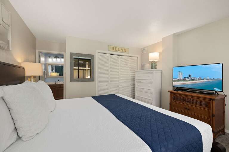 Relax and recharge in the spacious bedroom featuring a king bed, TV, and plenty of storage for your stay.