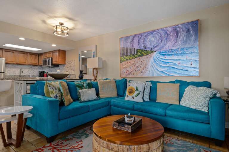 Relax on the spacious sectional surrounded by cheerful coastal décor, with the kitchen and dining area conveniently nearby.