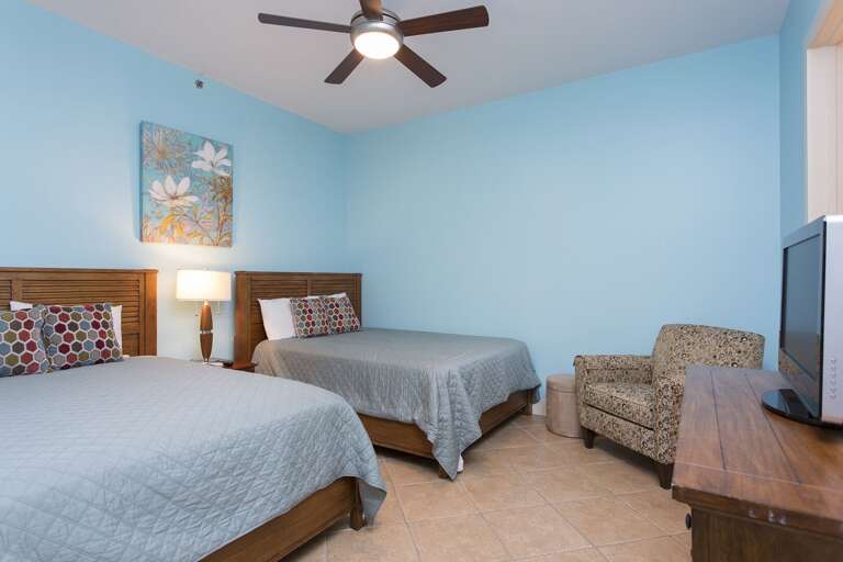 Guest bedroom with two full beds  and TV.