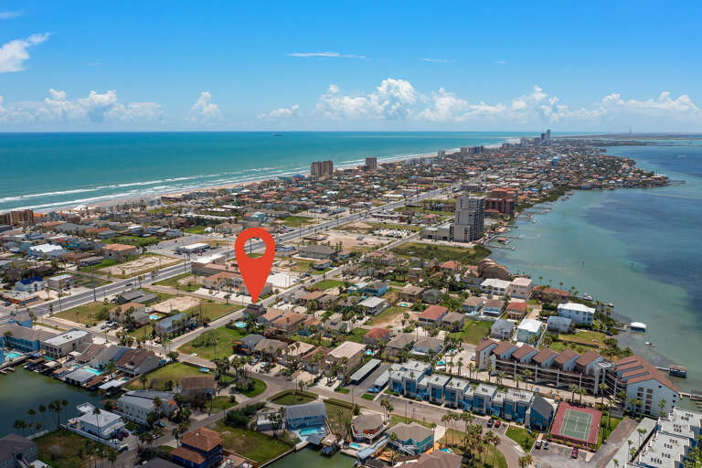 Aerial of the house, bay to the right and the beach to the left.