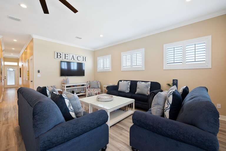 Spacious living room with ample seating for you and your guests around a large flat screen TV.