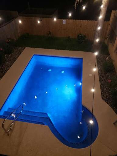Night View Of A Lit Swimming Pool With String Lights