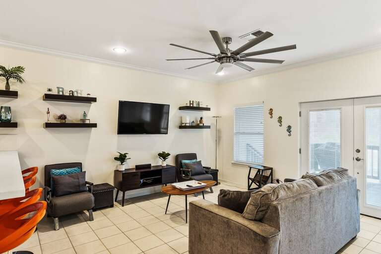 Living room with flat screen TV and access to the back balcony that has stairs leading down to the pool area!