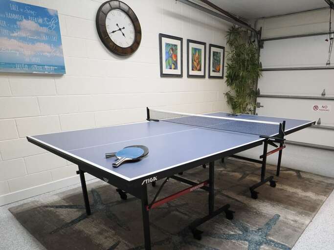 Table Tennis Setup In Tidy Basement Room, Two Paddles Poised For Play Table Tennis Setup In Tidy Basement Room, Two Paddles Poised For Play