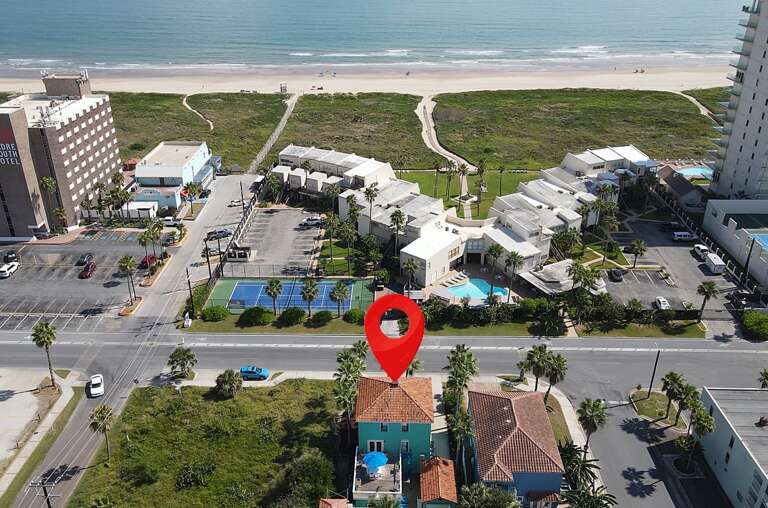 Aerial View Showcasing Seaside Structure Surrounded By Streets And Sand