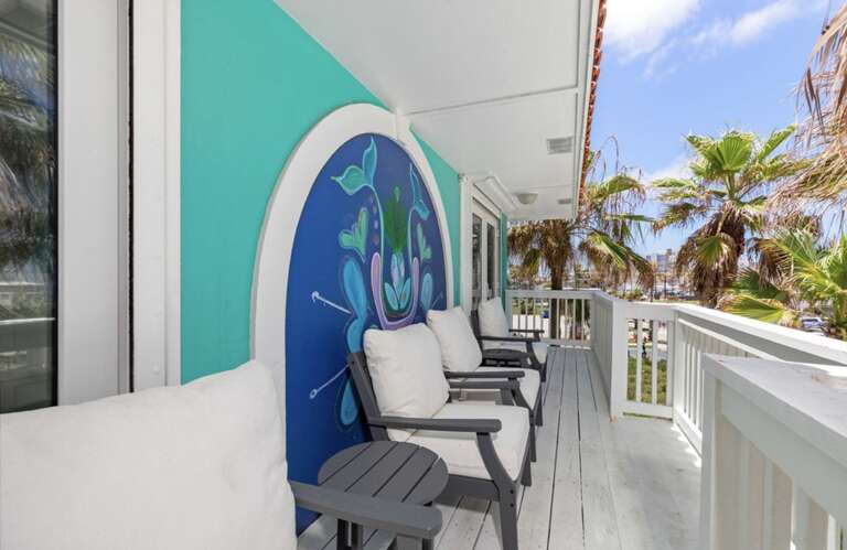 Balcony With Chairs And Ocean-themed Mural At A Vacation Rental