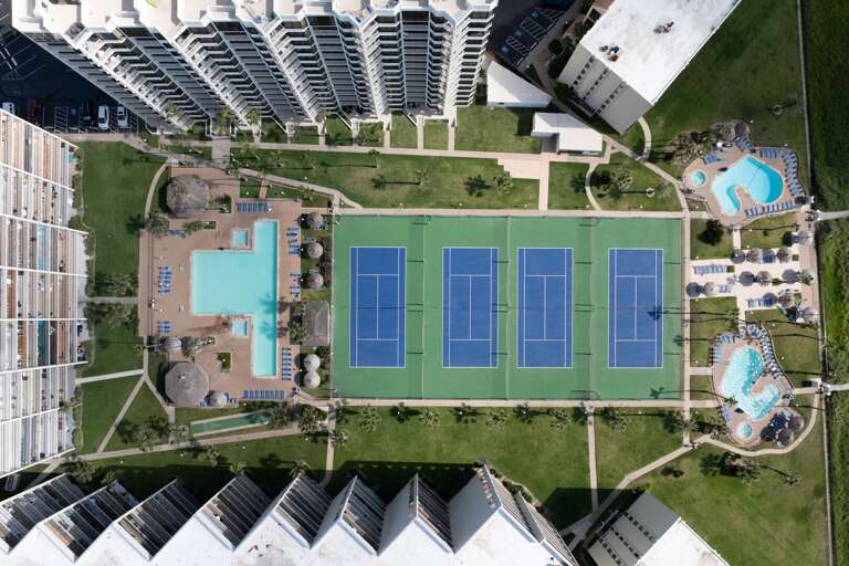 An aerial view showcases the property's tennis and pickleball courts along with the surrounding resort amenities.
