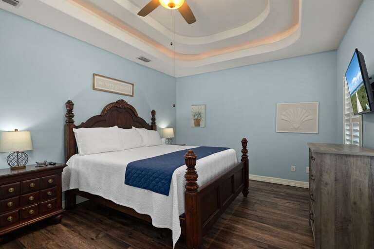 Spacious master suite with elegant furnishings, a comfortable king bed, tray ceilings, and flat screen TV.