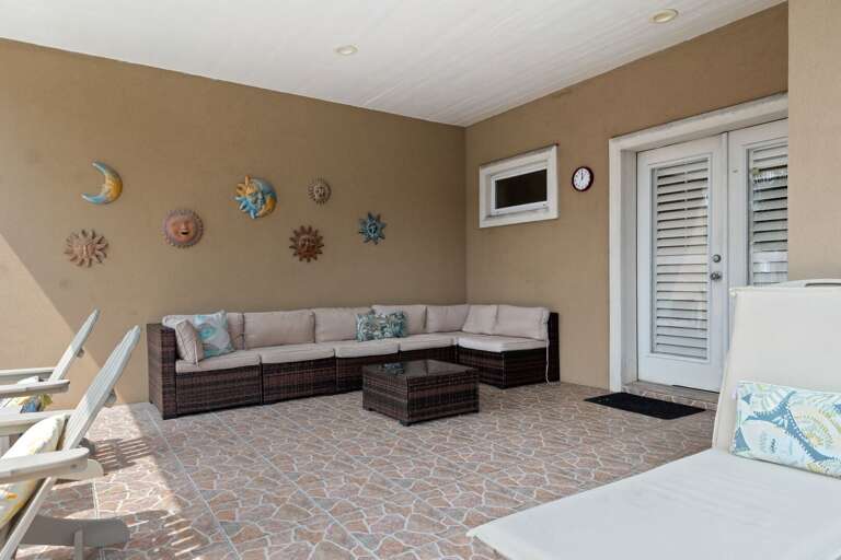 Spacious covered patio with stylish seating, perfect for shaded outdoor relaxation beside the private pool.