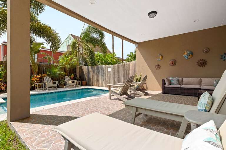 Relax in the shaded patio lounge overlooking the sparkling heated private pool and lush tropical landscaping.