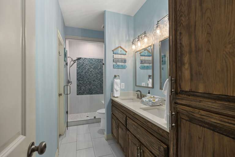 Beautiful master ensuite with a large double-sink vanity, stylish lighting, and a walk-in tiled shower.