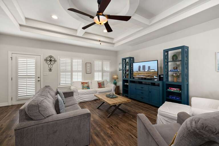 Bright and inviting living room featuring tray ceilings, coastal décor, and plenty of comfortable seating for the whole group