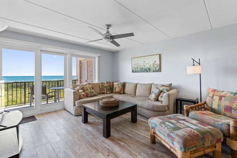 Bright oceanfront living room with floor-to-ceiling views of the Gulf, comfy seating, and modern coastal décor.