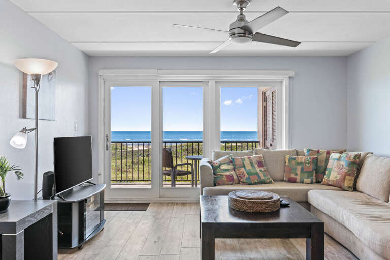 Cozy ocean-view living space with natural light, coastal décor, and a flat-screen TV for relaxing evenings.