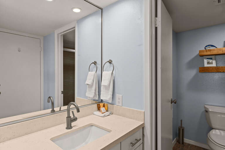 Modern bathroom with fresh towels, bright lighting, and clean coastal style.