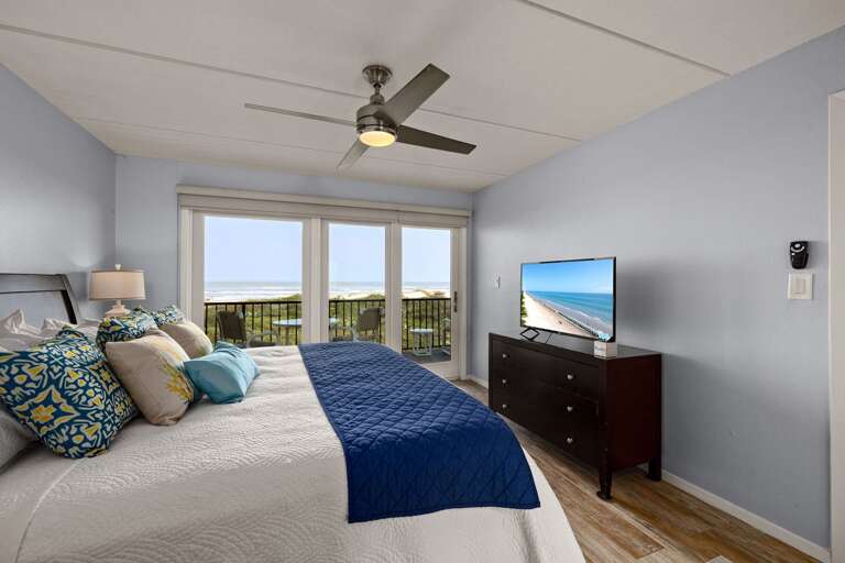 Spacious master suite featuring a king bed and beautiful ocean views through large windows.