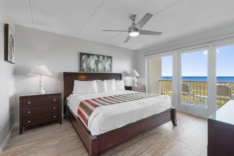 Spacious master suite featuring a king bed and beautiful ocean views through large windows.