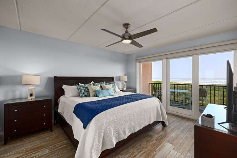 Spacious master suite with a king bed, flat-screen TV, and direct access to ocean views for a relaxing retreat.