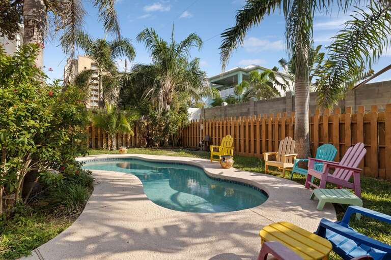 Tropical Poolside Paradise Punctuated By Colorful Chairs And Lush Greenery