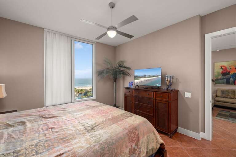 The master bedroom features a king bed and natural light pouring through large windows with views to the Gulf of Mexico