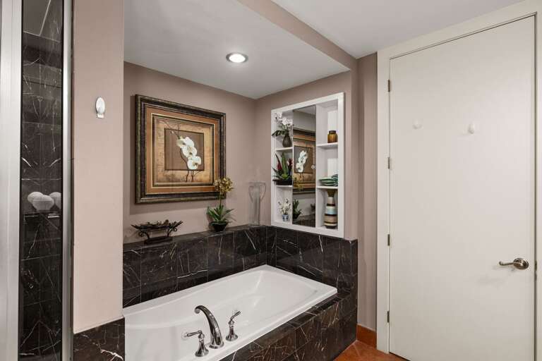 Unwind in the stunning master bathroom, featuring a deep soaking tub perfect for relaxing after a day at the beach