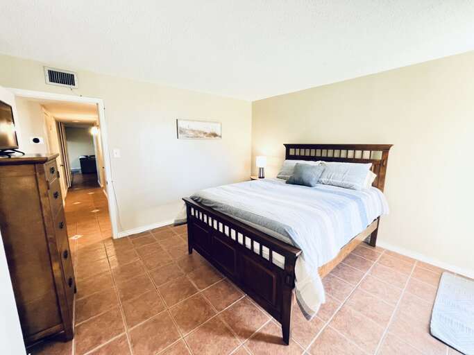 Second bedroom featuring a comfortable queen bed, tile flooring, and a calm, relaxing atmosphere.