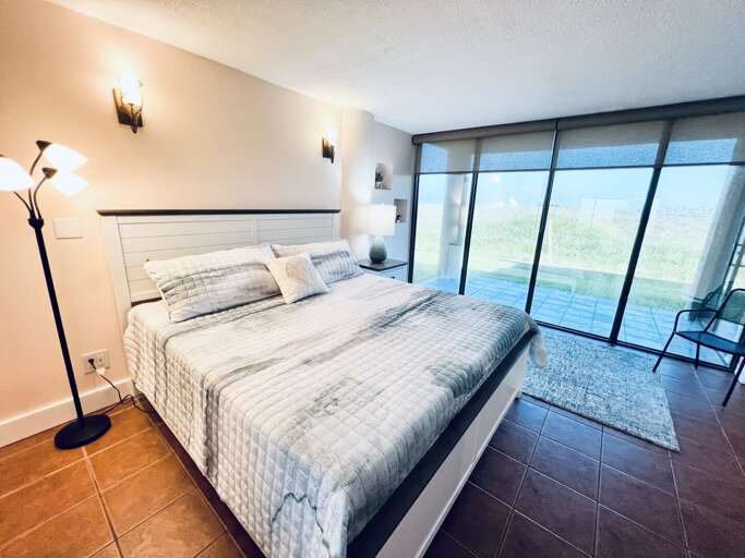 Comfortable primary bedroom with a cozy king bed and sliding glass doors leading to a private patio with outdoor seating.