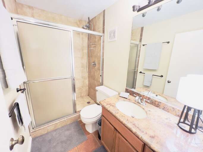 Guest bathroom featuring a tub and shower combination, granite vanity, and tile flooring.