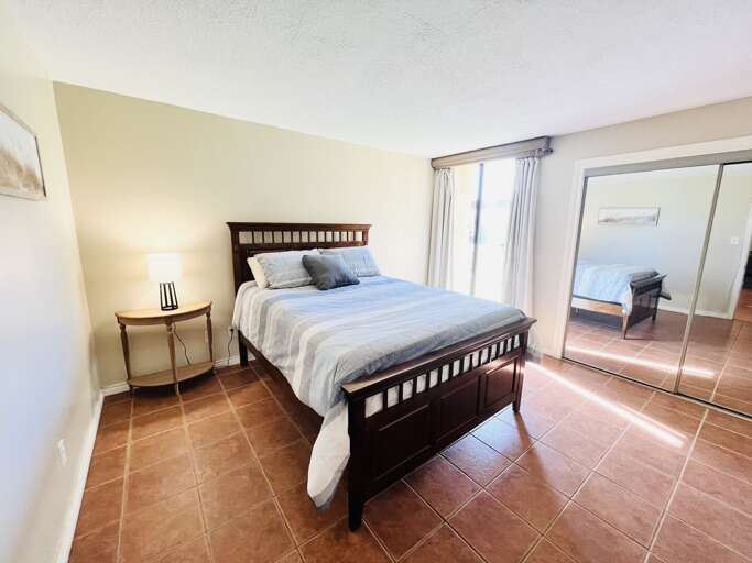 Second guest bedroom featuring a queen bed, tile flooring, and ample natural light.