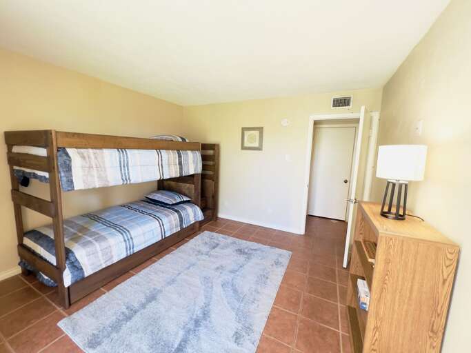 Third guest bedroom with twin-over-twin bunk beds, with a twin trundle, tile flooring, and a bright, open layout.