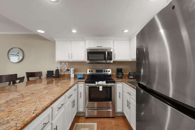 Kitchen With Stainless Steel Appliances, Granite Countertops, And Bar Stools