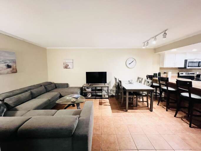 Sea Vista I #102 features an open-concept living and dining area with comfortable seating, flat-screen TV, and an equipped kitchen, ideal for family gatherings.