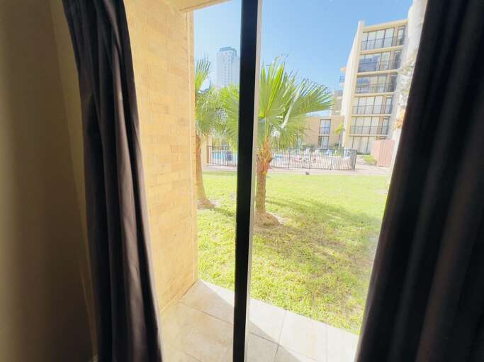 View from the patio looking out toward the landscaped grounds and resort-style community pool area.
