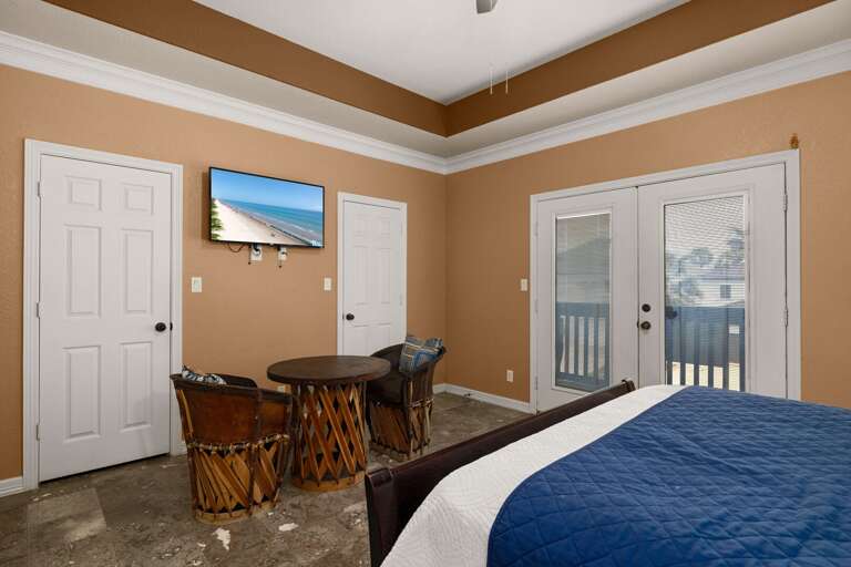 Bedroom with seating area, TV, and balcony access
