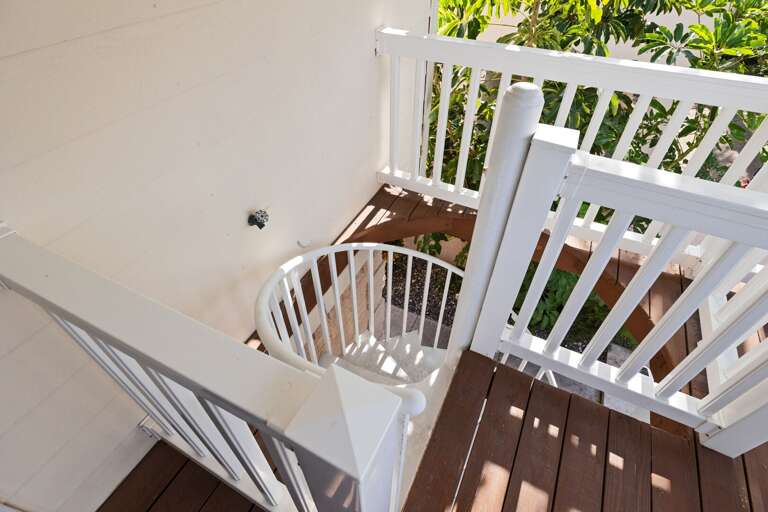A spiral staircase connects the balcony to the pool area