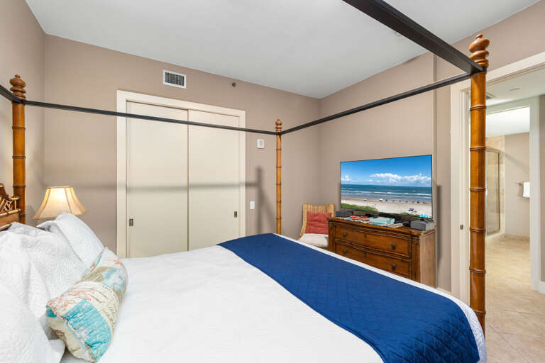Bright guest bedroom with queen bed and TV