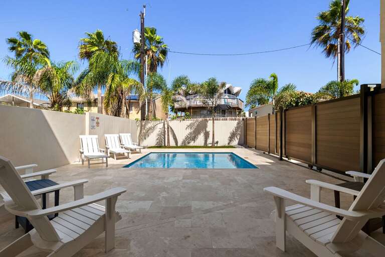 Enjoy your own private backyard retreat with a sparkling pool, comfortable loungers, and tropical surroundings.