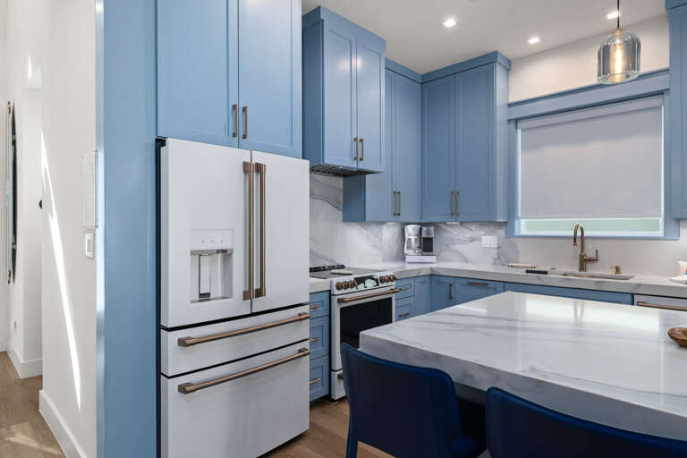 The fully equipped kitchen features blue cabinetry, stainless steel appliances, and generous counter space.