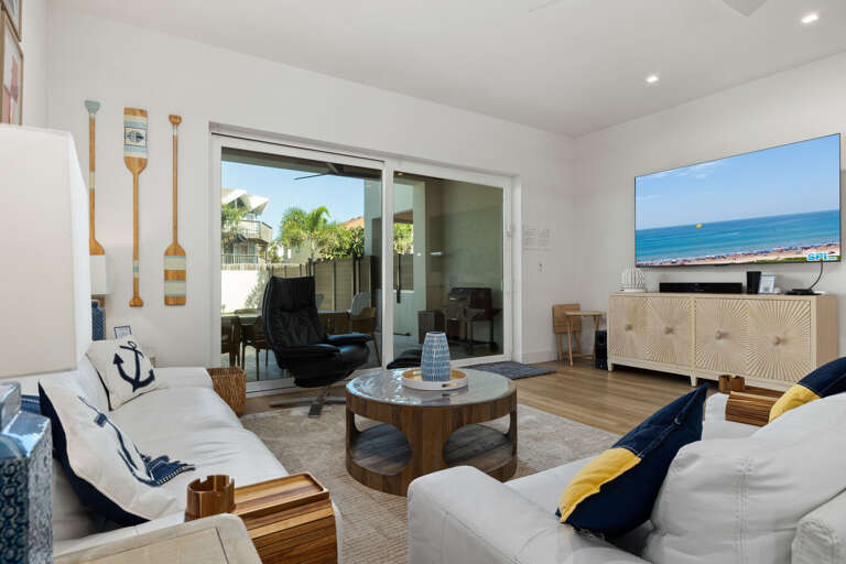 Relax in the spacious living room with comfortable seating, a mounted TV, and sliding doors to the outdoor patio.